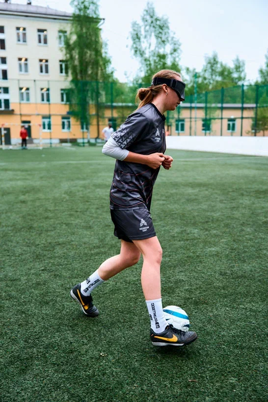 Всплывающее фото. На снимке студентка играет в футбол в очках дополненной реальности