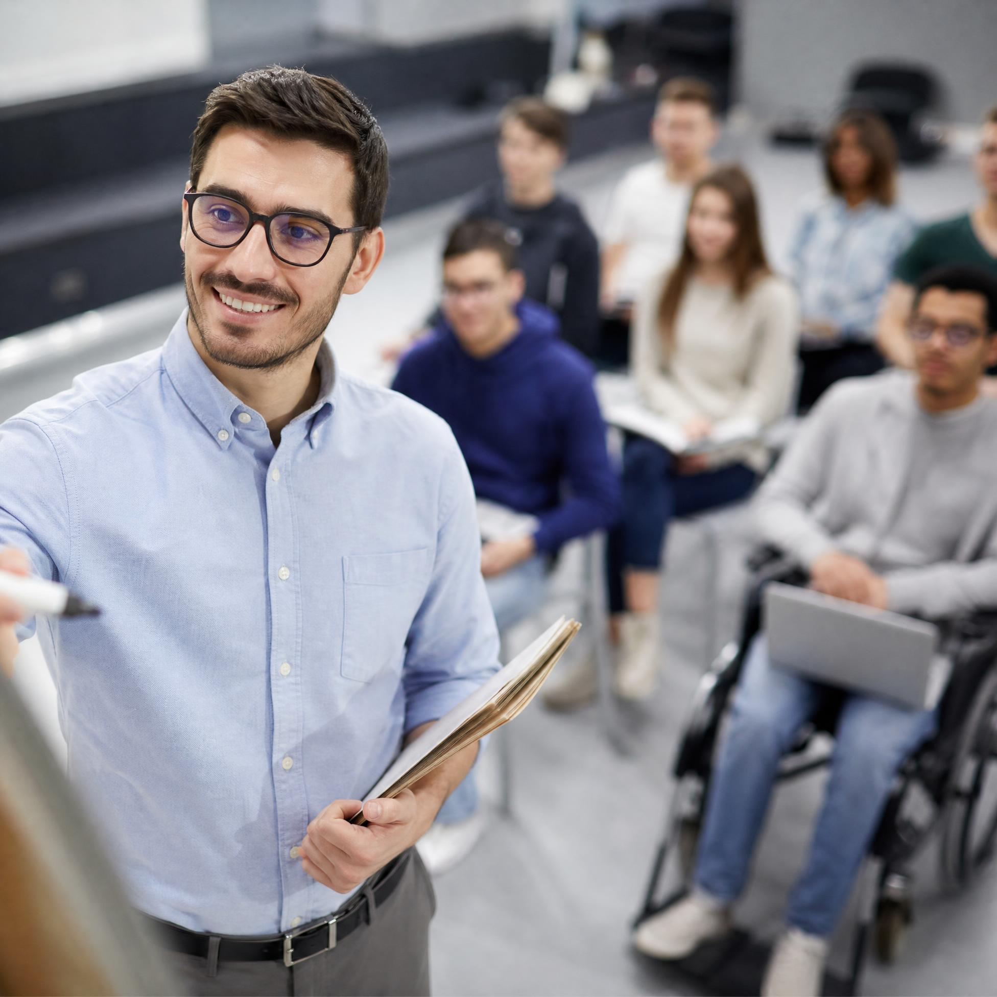 На изображении Преподаватель проводит занятие для группы студентов, включая студента на инвалидной коляске